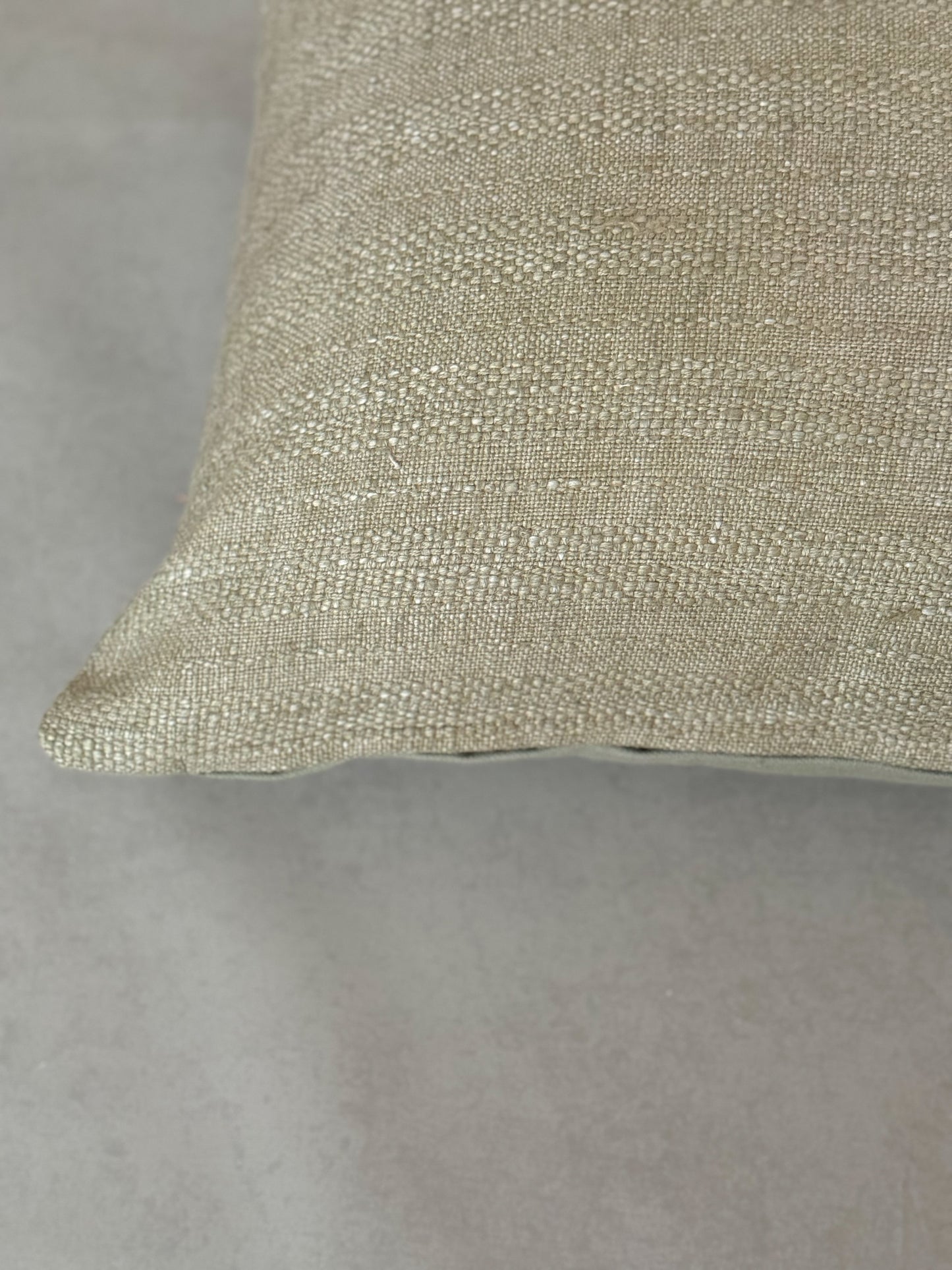 Close up of a textured natural green cotton oblong cushion for sofa, chair or bed.