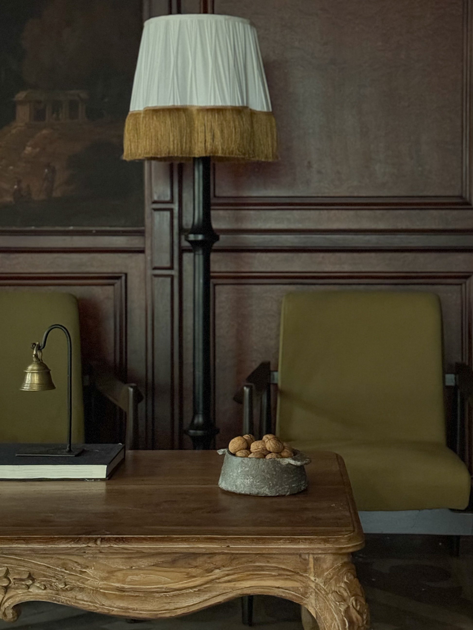 A brass bell with black metal stand styled on a center table.