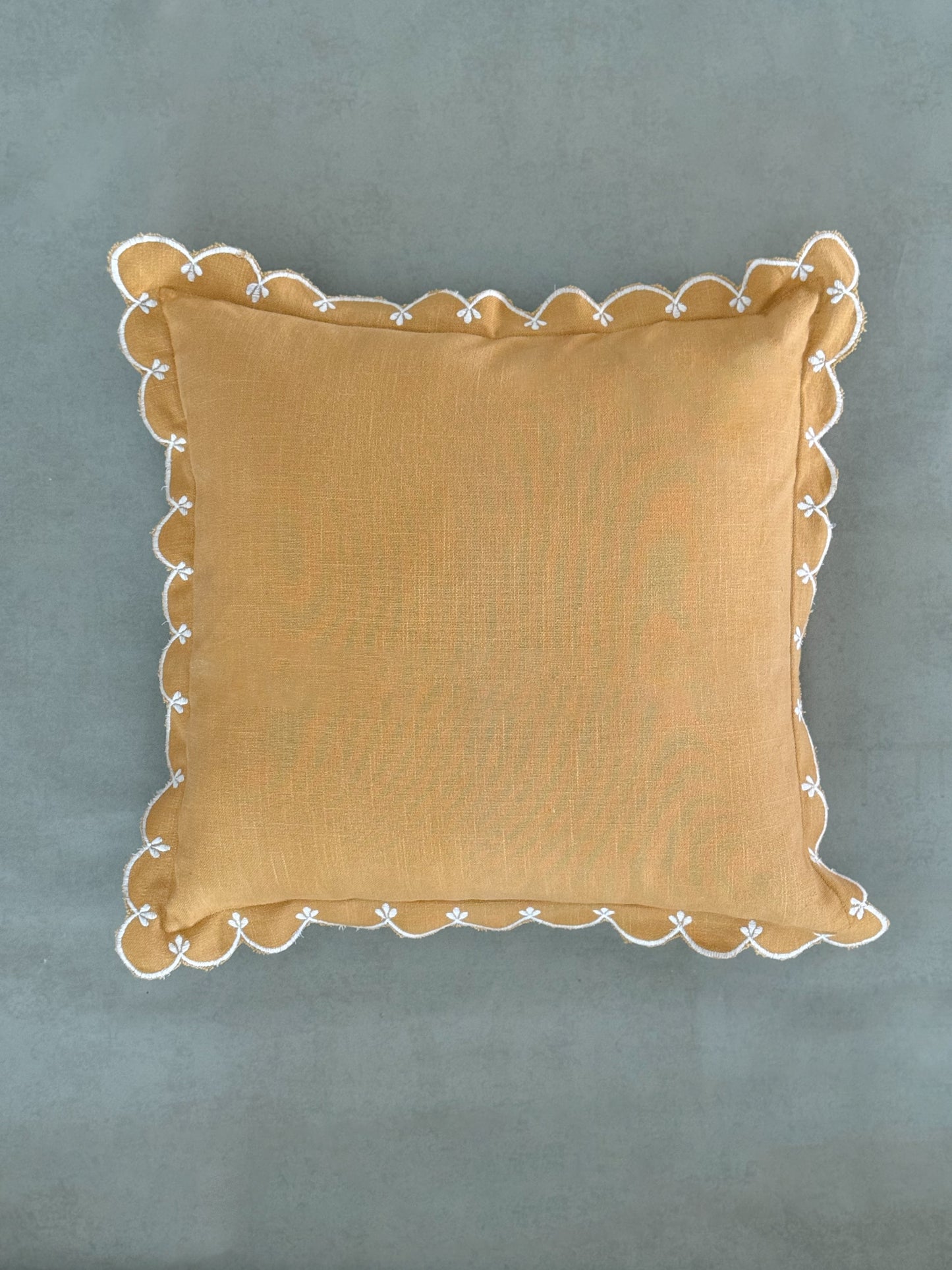 Yellow cushion with curved, wave-like scalloped edge detailing.