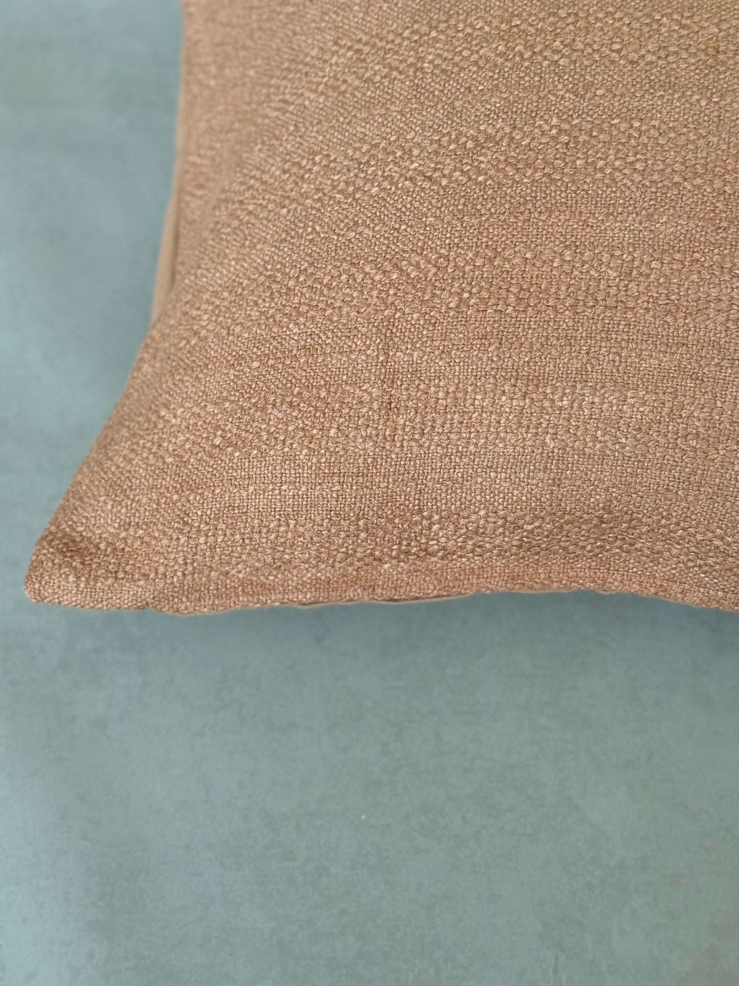 Close up of a textured natural brown cotton oblong cushion for sofa, chair or bed.