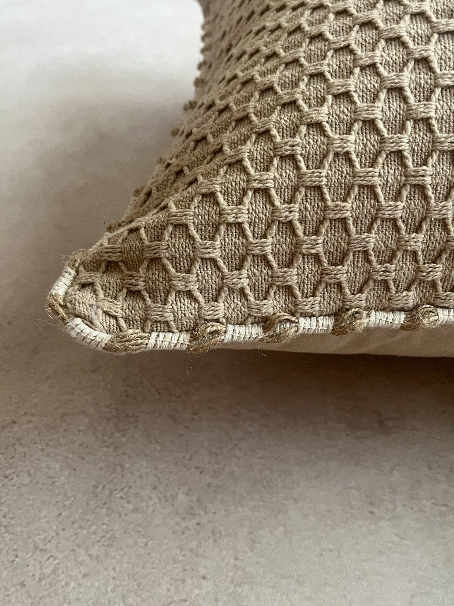 Beige cushion cover with white piping detail