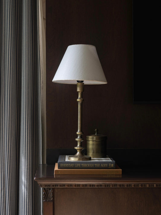Vintage-style lamp with white shade and brass stand in antique gold finish.