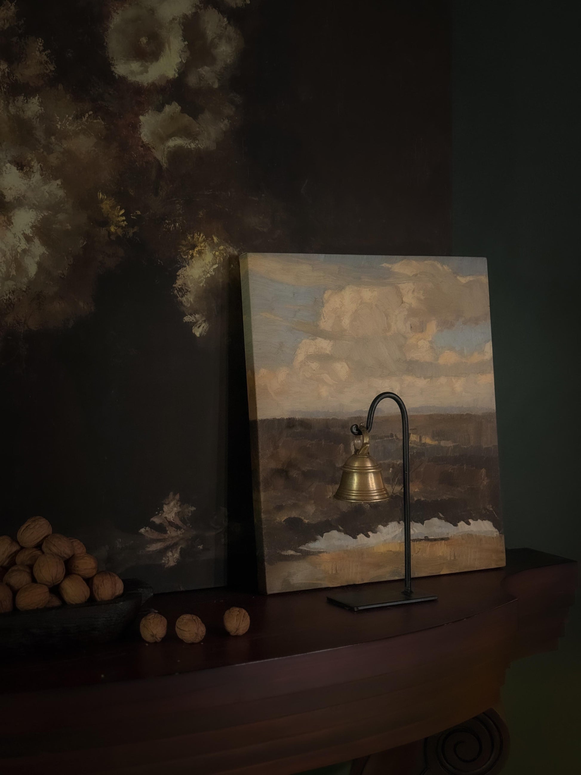 A brass bell with black metal stand for home decor with a touch of vintage charm, styled on a console table.