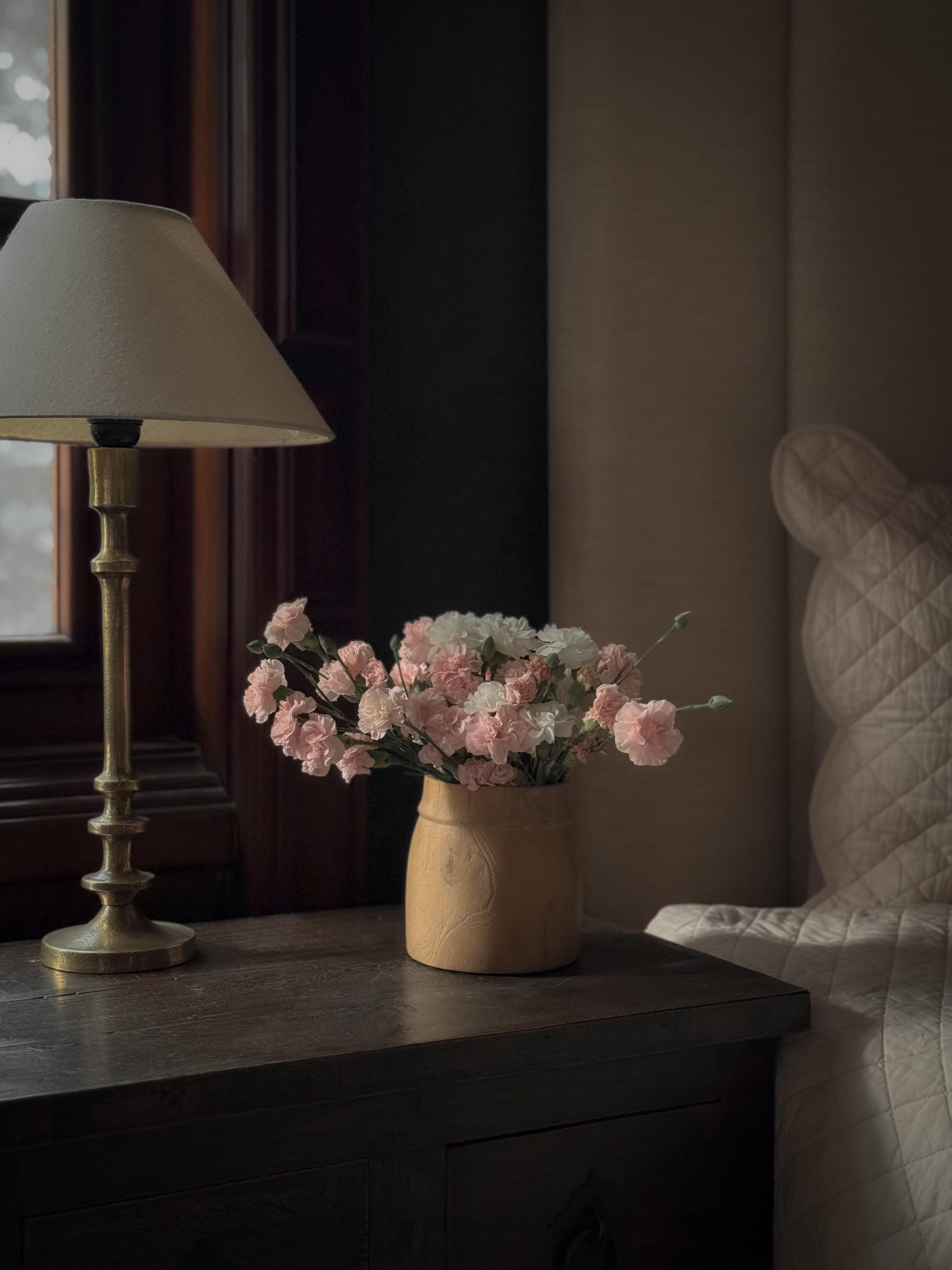 Vintage-style lamp with white shade and brass stand in antique gold finish styled with a wooden flower vase.