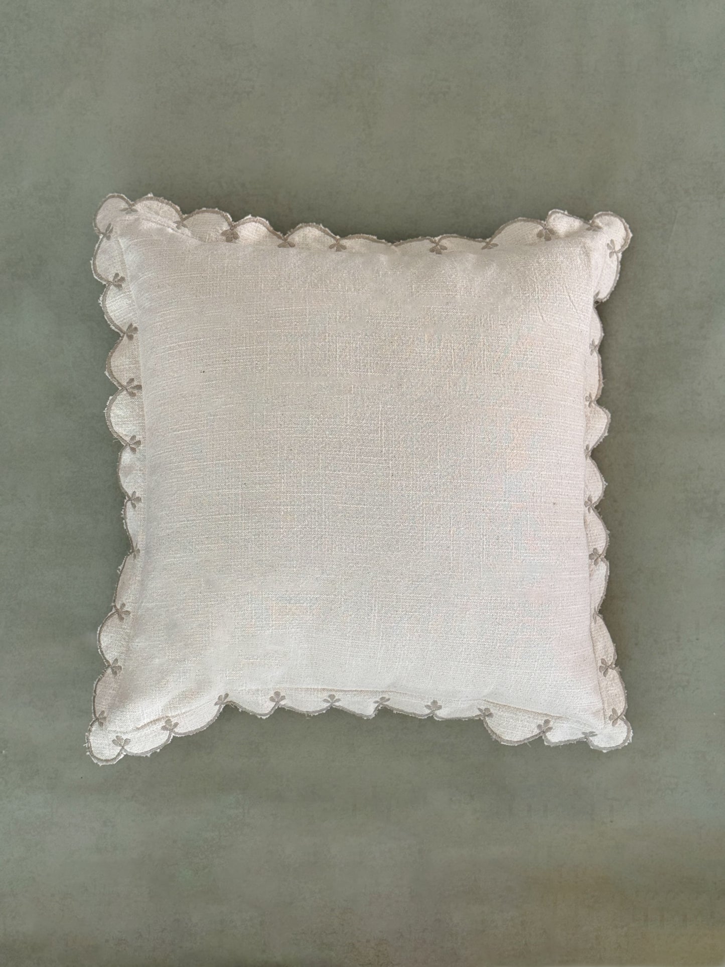 Ivory cushion with curved, wave-like scalloped edge detailing.