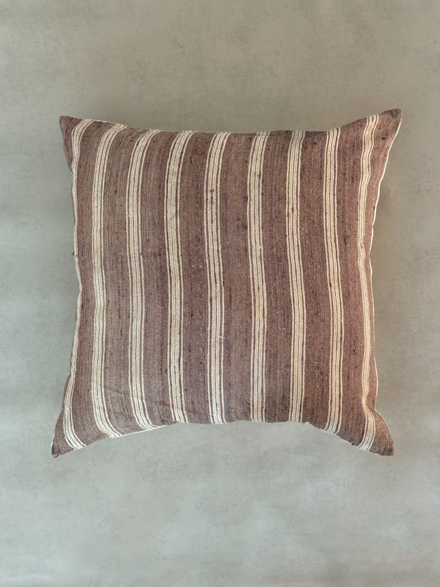 Striped pillow with brown and beige pattern on a plain background