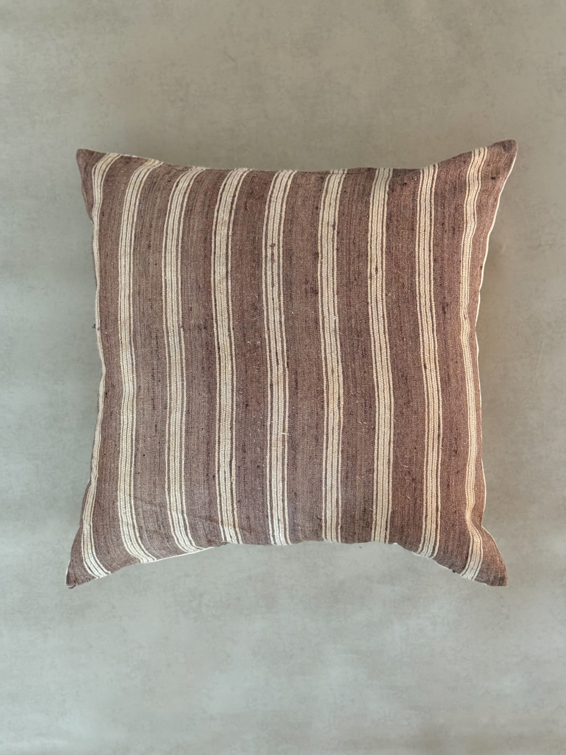 Striped pillow with brown and beige pattern on a plain background