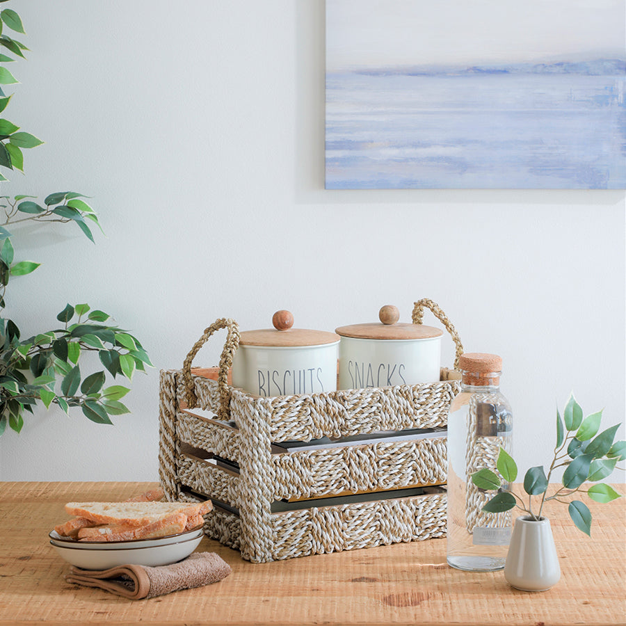 Seaweed rope basket, Handwoven storage crate, Natural woven organizer, Ceramic kitchen canisters, 
Snack and biscuit storage jars, 
Airtight ceramic containers with wooden lids, Ceramic breakfast bowl, 
Rustic ceramic bowl set, Farmhouse style kitchen jars, Clear glass water bottle, Minimalist glass carafe with cork top, Small ceramic bud vase, 
Faux greenery in vase.



