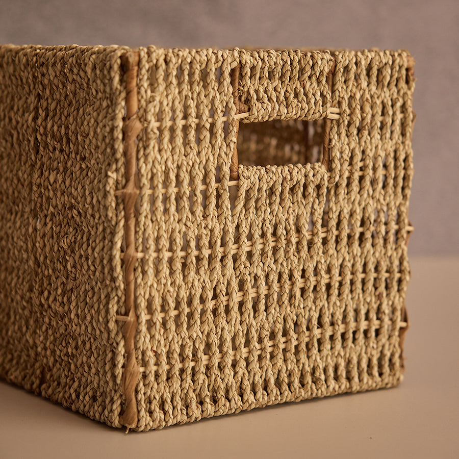 handwoven storage basket, natural seagrass cube basket, wicker organizer with handle, rectangular woven storage bin, eco-friendly woven container, rustic handwoven basket for shelves, seagrass basket with cutout handles, sustainable storage solution for home, handmade woven desktop organizer, minimalist cube wicker bin.
