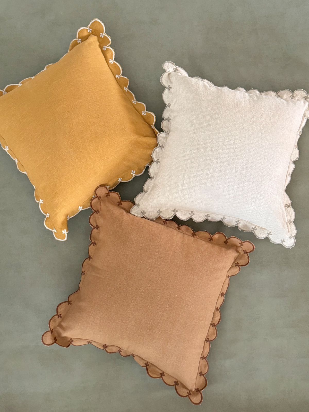 Decorative cushions in yellow, ivory, and brown with curved, wave-like scalloped detailing.