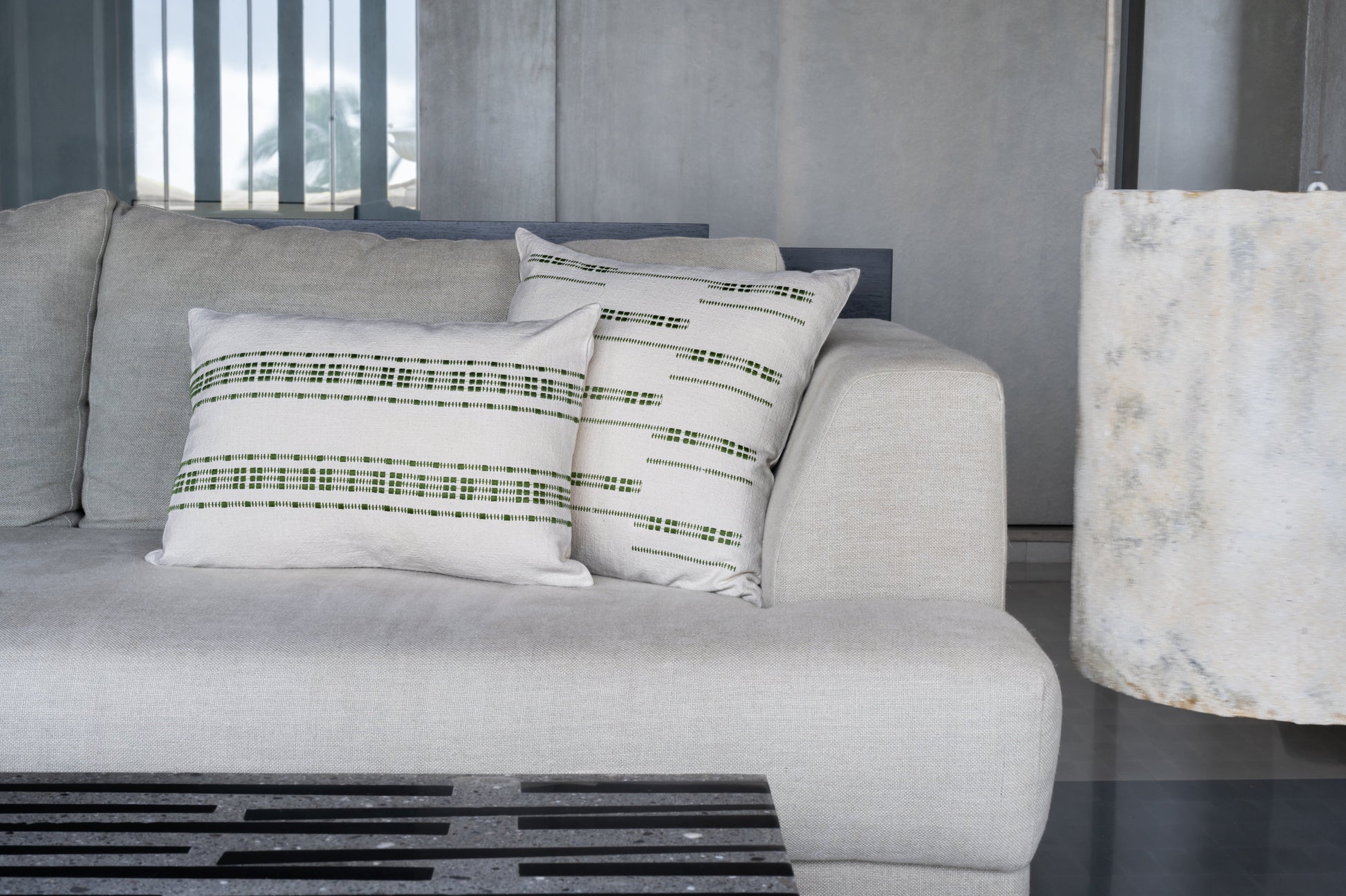 Green embroidered cotton lumbar cushion cover placed next to a green embroidered cotton cushion cover on a couch
